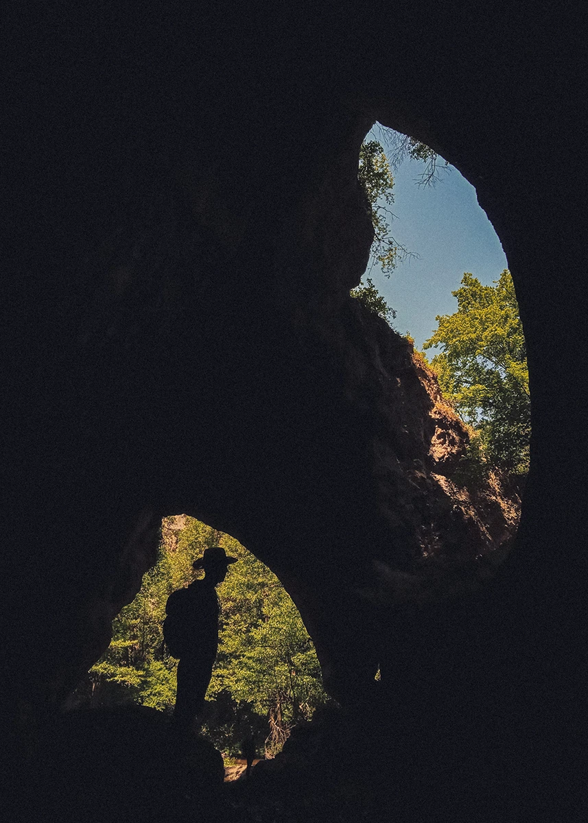 The silhouette of a hiker resting inside a cave and natural bridge in Eastern Serbia during a hiking adventure